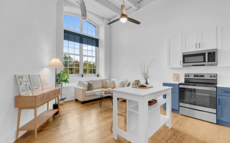a living room with a white couch and a table and a kitchen area